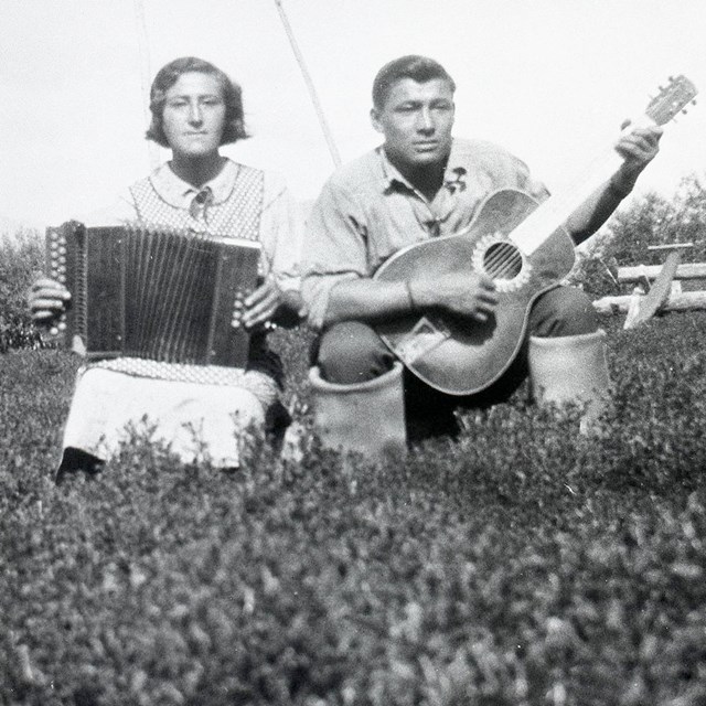 Historic image of woman playing accordion and man playing guitar.