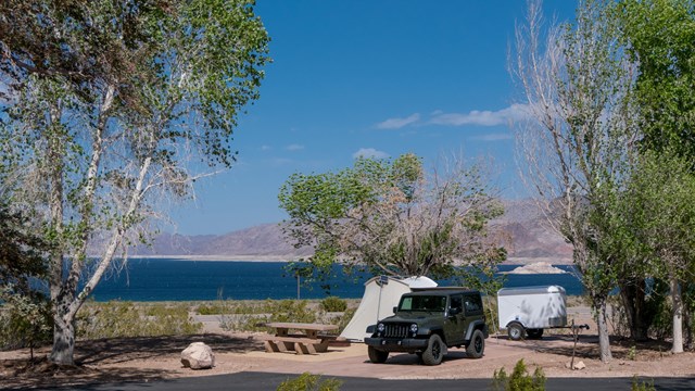 A car with a tent and a large body of water.