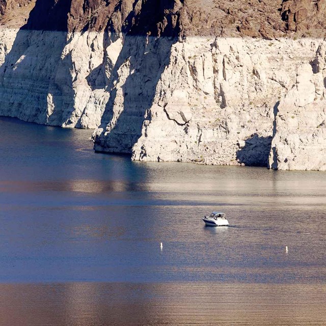 A boat cruises near the white band along the shore of Lake Mead NRA