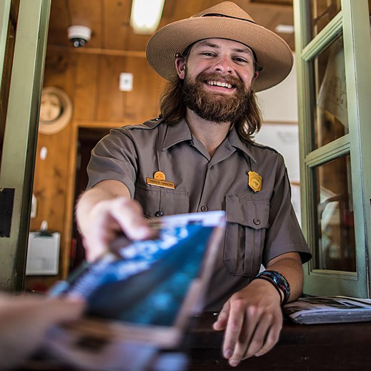 A park ranger handing a brochure to a visitor.