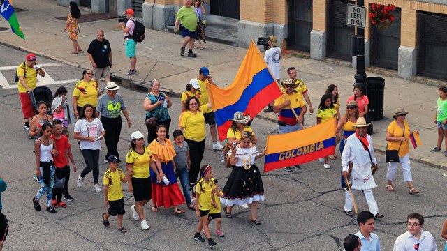 Colombians march down the street and on the sidewalk for the parade. 