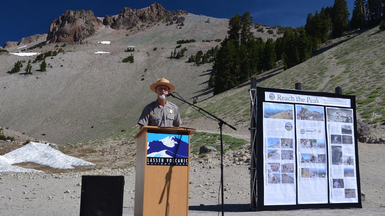 ranger talking at a podium with Lassen peak behind