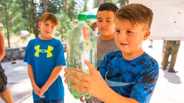 A boy holds a soda bottle for a science experiement.