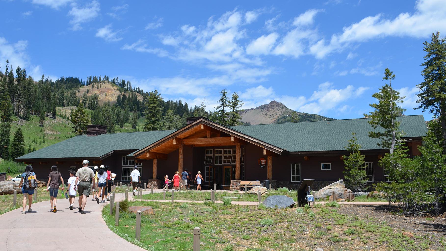 People walking into the Kohm Yah-mah-nee Visitor Center with clouds in the sky
