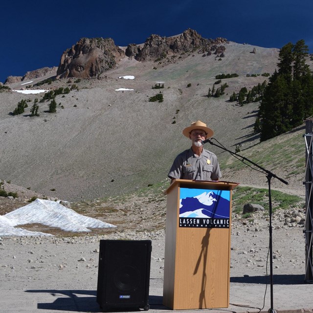 ranger talking at a podium with Lassen peak behind