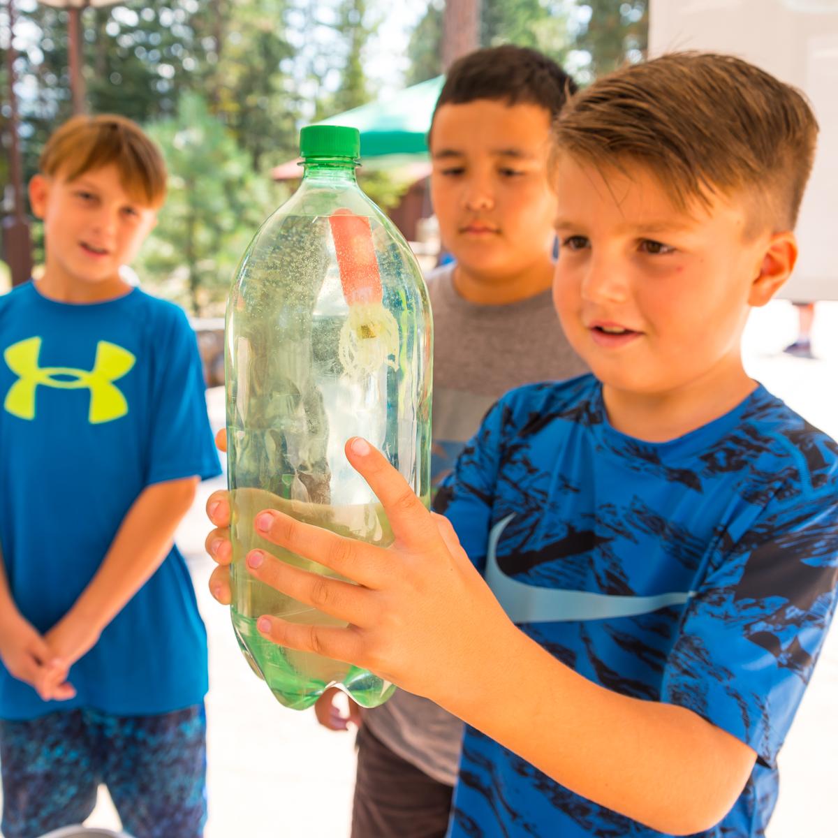 A boy holds a soda bottle for a science experiement.