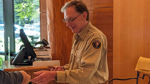 A park volunteer checks a park pass behind handed to them.