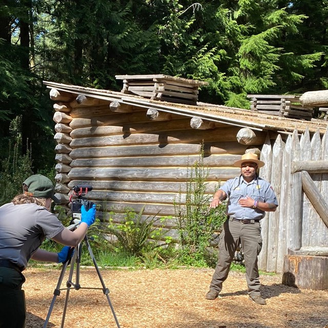 One ranger filming another ranger presenting in front of Fort Clatsop