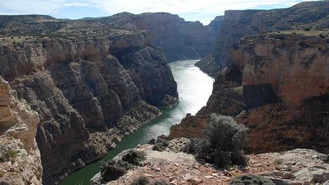 river reflecting sunlight between vertical canyon cliffs