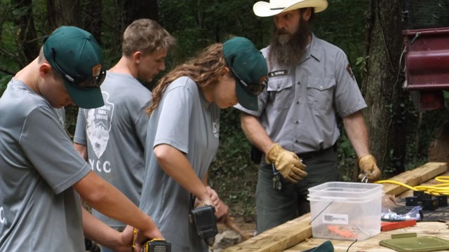 Three YCC youths using handtools, Maintenance worker supervises