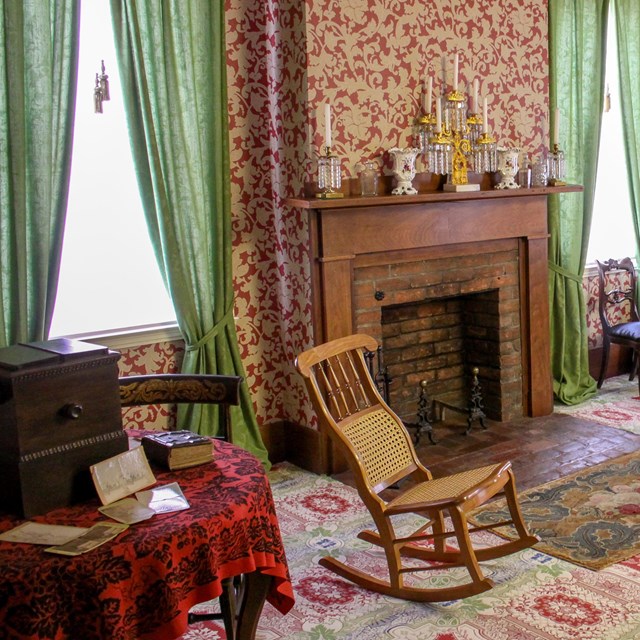 Lincoln Home sitting room with colorful carpet, red and white patterned wallpaper, and green curtain