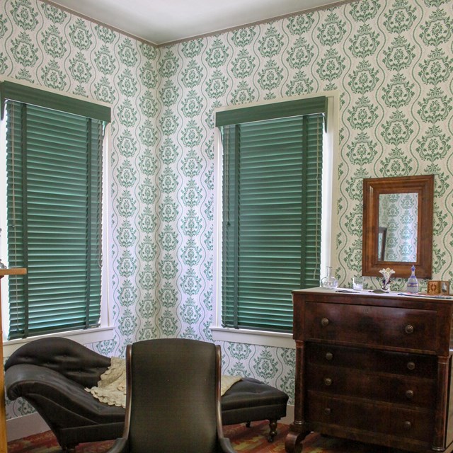 Lincoln Home guest room with off-white wallpaper with green repeating crest-pattern