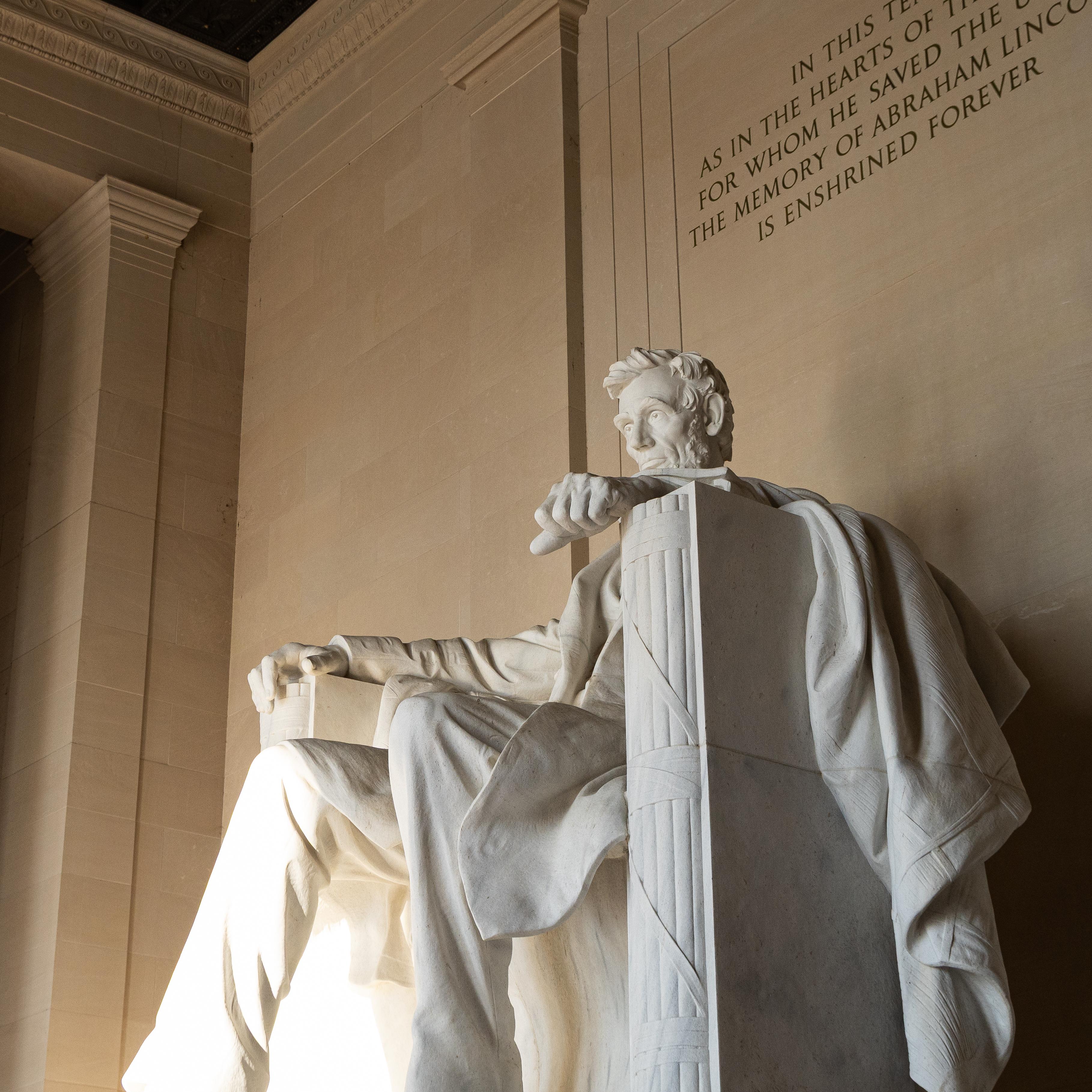 A large statue of Abraham Lincoln inside a tall room with columns.