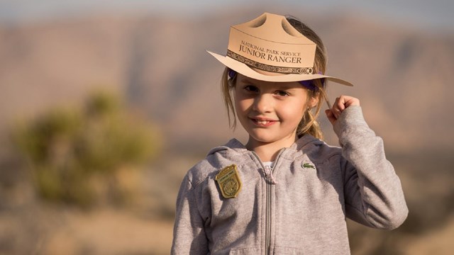 Junior Ranger wearing a paper hat and badge