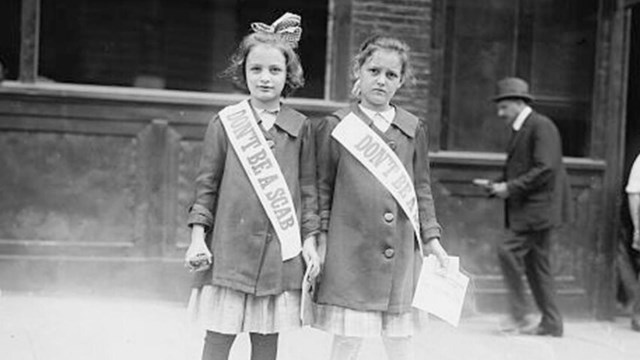 Black and white photo of two young girls standing next to each other hearing sashes