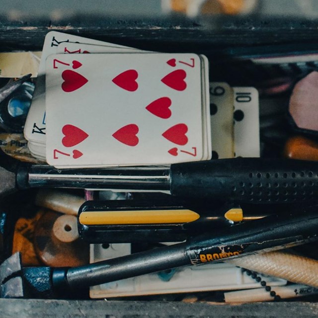 Tool box full of different small items like playing cards, fuses, and pencils