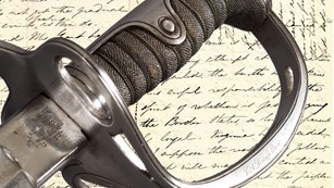 Detail of saber handle engraved C.A. Longfellow over background of manuscript letter