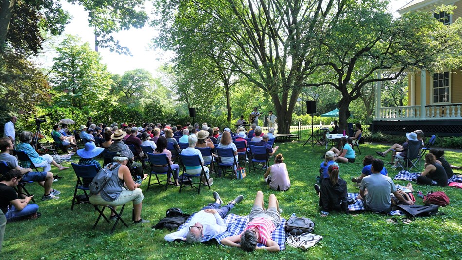 Crowd seated on chairs and blankets on lawn to watch concert