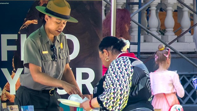 A park ranger speaks to a visitor under and outdoor tent