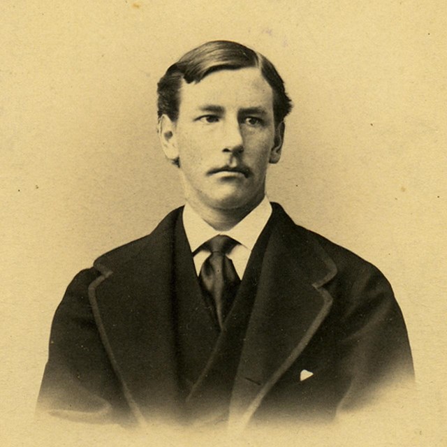 Bust-length photograph of young man with mustache