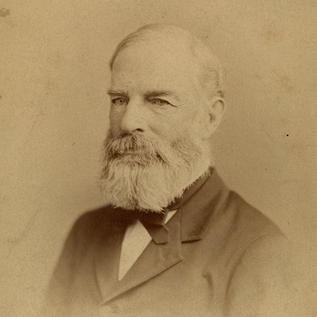 Bust-length portrait of man in suit with a beard
