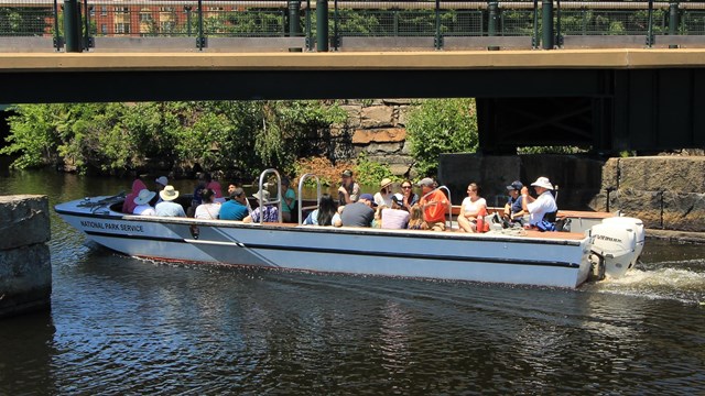 Visitors, a captain and ranger on a boat in a canal