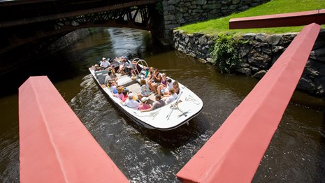 A boat tour full of visitors enters a lock chamber