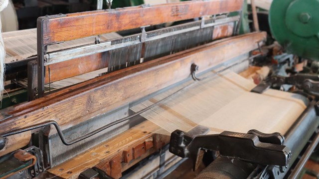 wood and metal machine with cloth coming out of it.