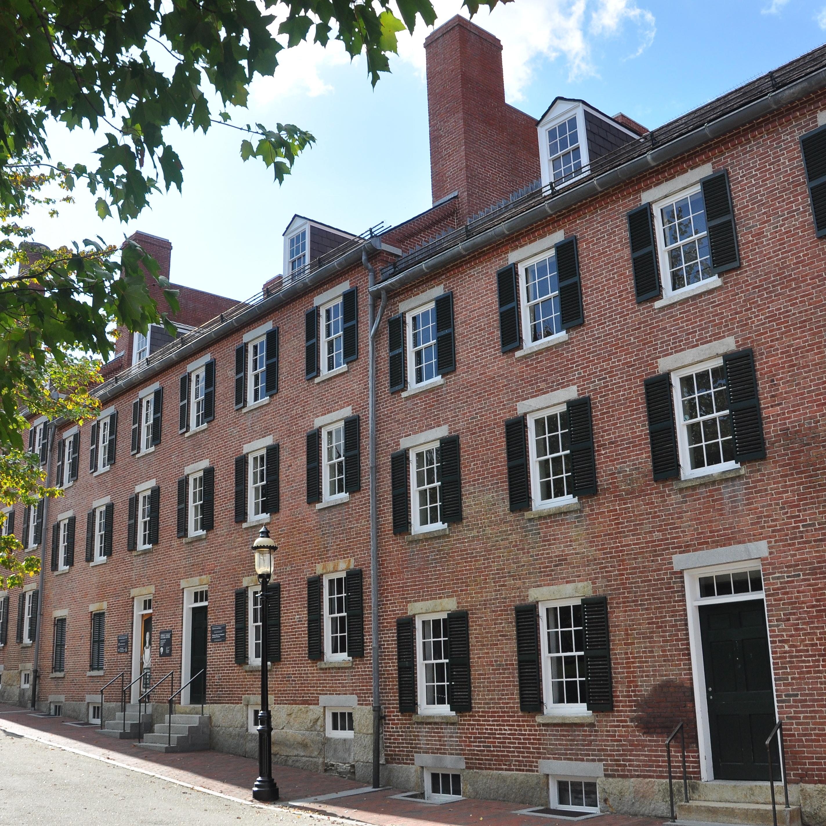 the exterior of a red brick building with a walkway and park in front