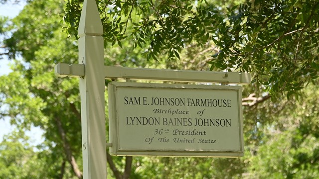 White sign that reads "Sam E. Johnson Farmhouse, Birthplace of Lyndon B. Johnson."