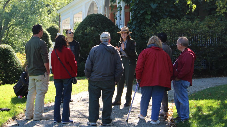 Ranger talks to a group of people outside of the mansion