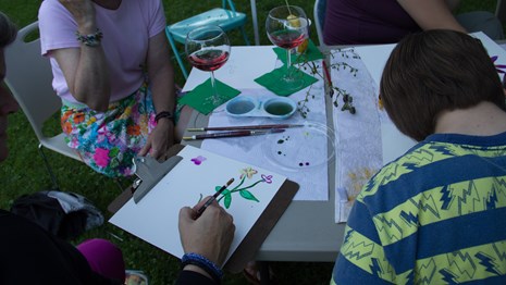 People sit around a table with watercolor flowers and red wine