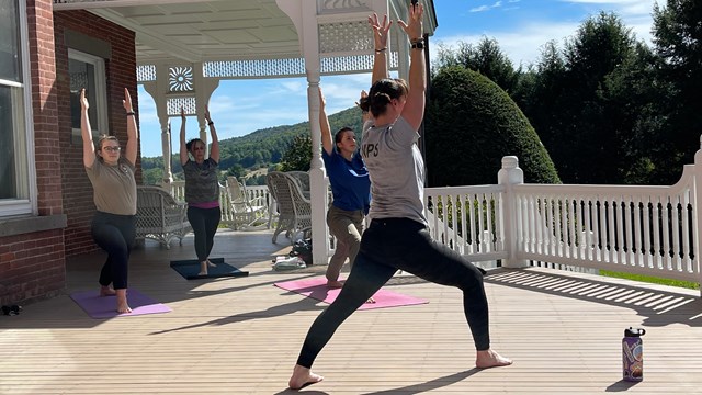 Yoga practice takes place with three people on mansion porch