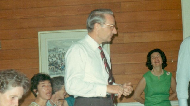 grainy color photo from 1970s of man in collared shirt and tie next to bowling lane