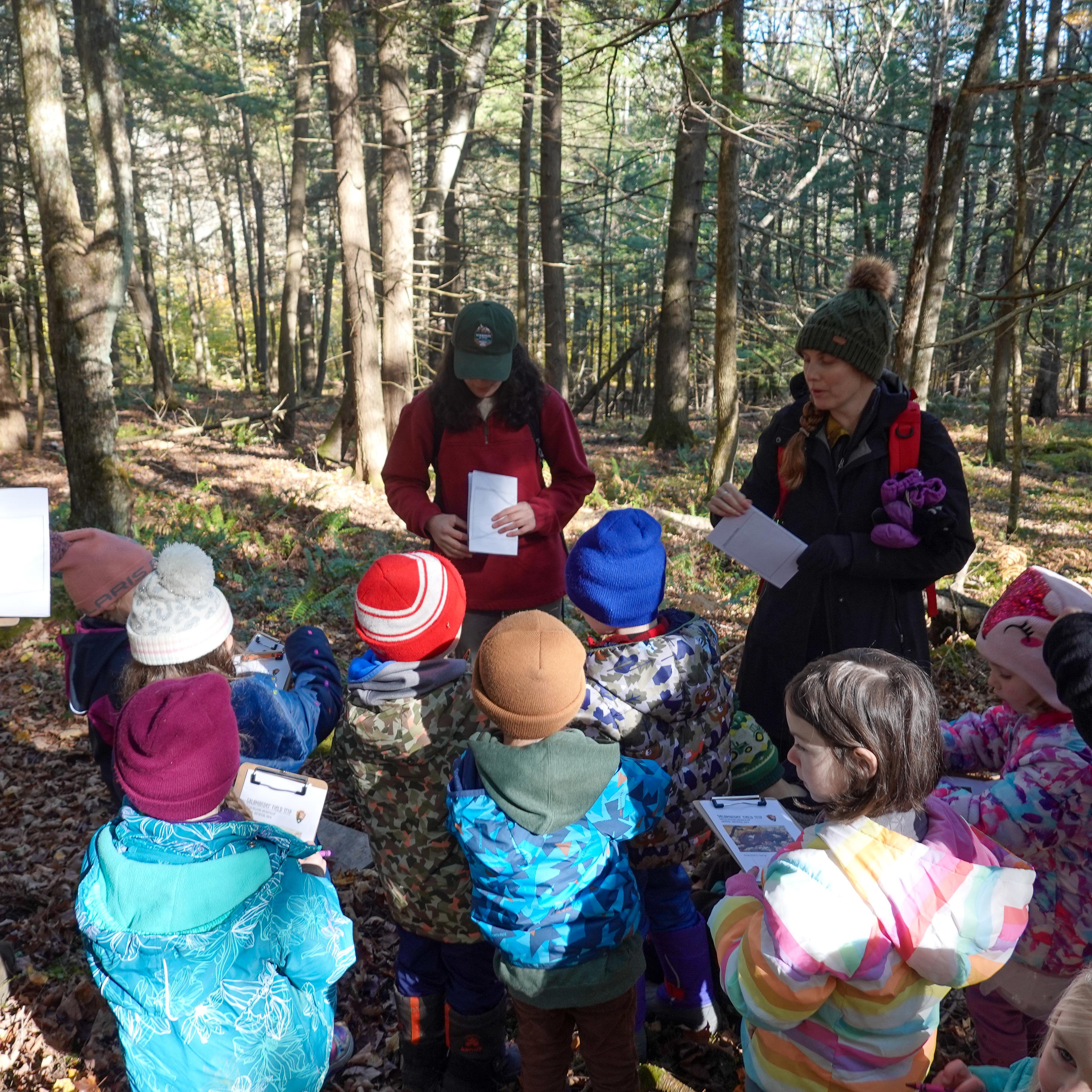 group of children listen to speaker on a hike
