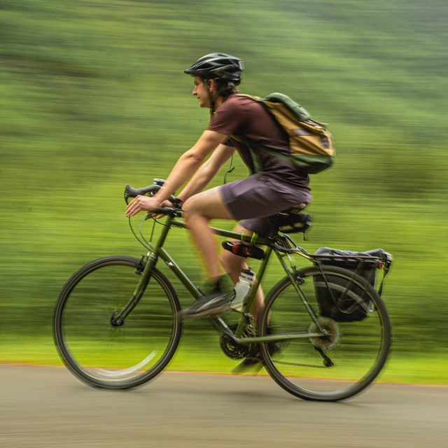 a man wearing a helmet bicycles on a path