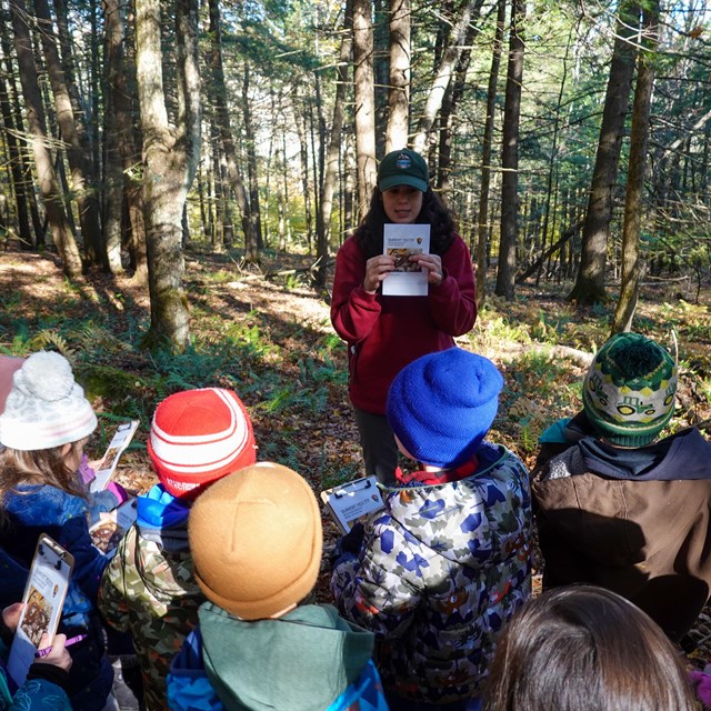 preschool students listen to a park staff member talking on the trail