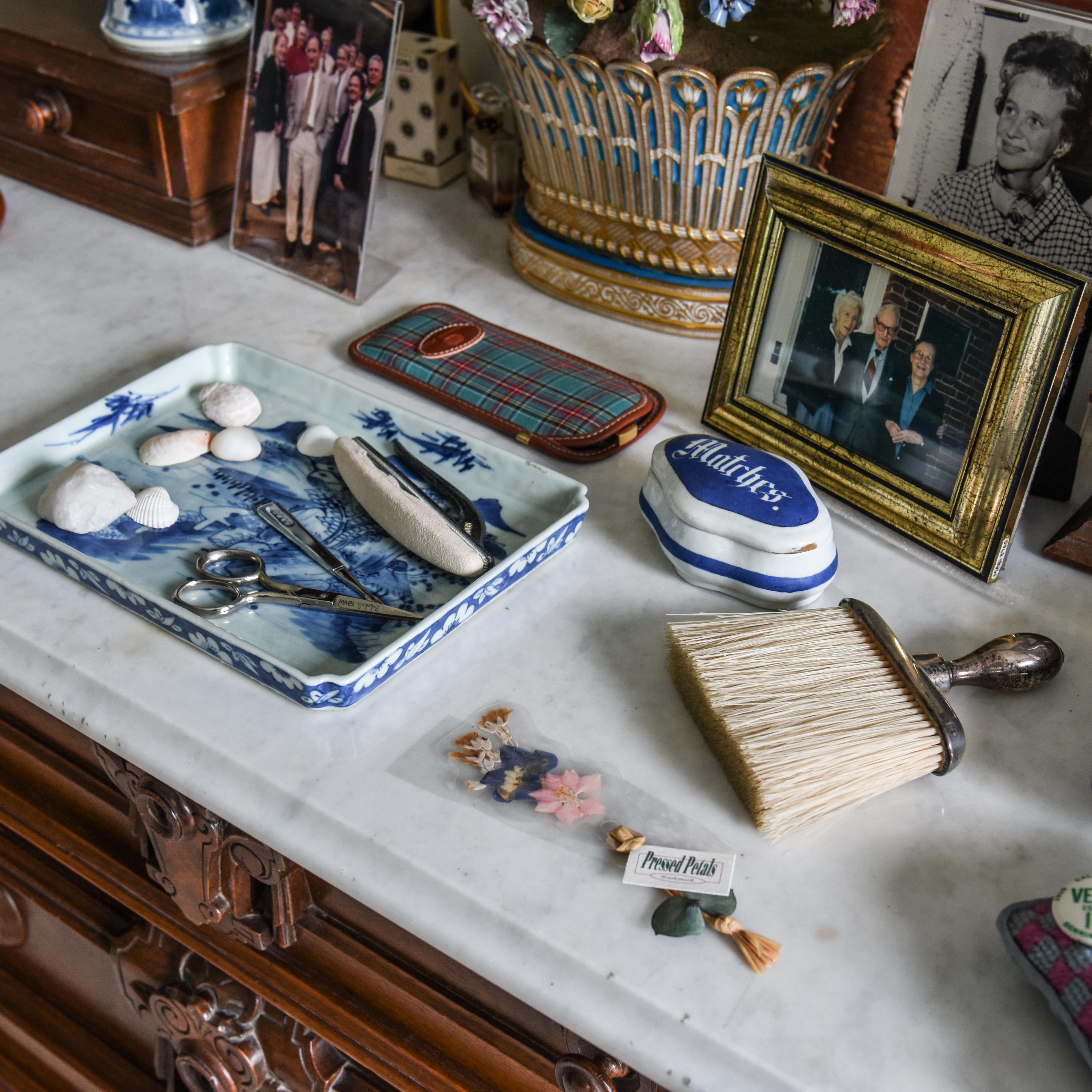 Close up of the top of a historic dresser with personal objects and family photos