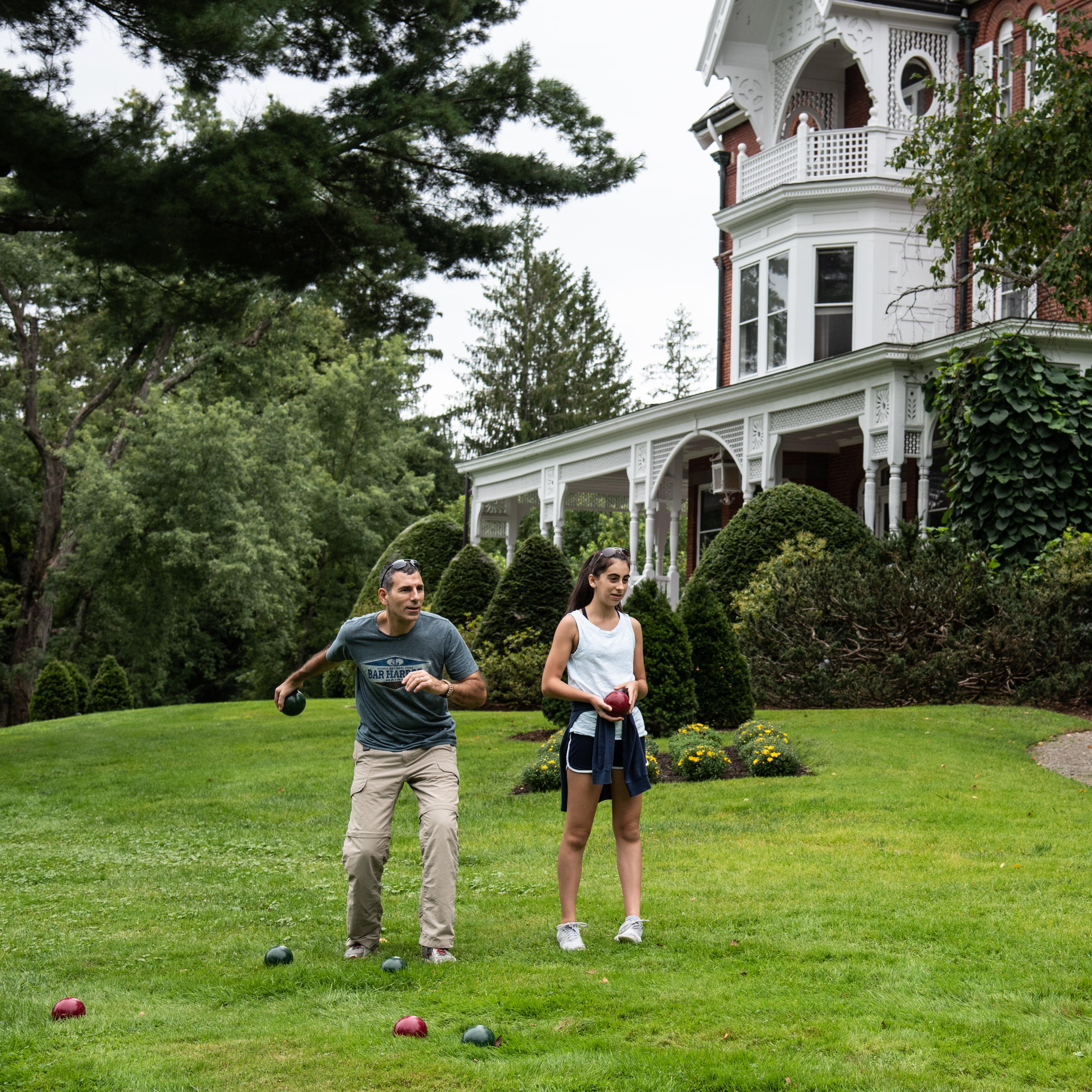 Two park visitors play bocce ball in front of MBR mansion
