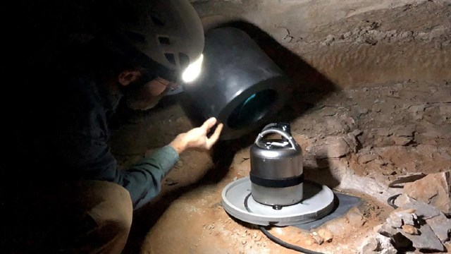 A man installs cables into the ground for seismic monitoring equipment