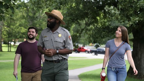 A park ranger walks down a trail with two visitors following. 