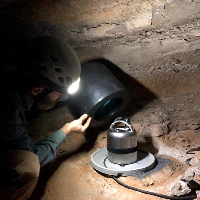 A man installs cables into the ground for seismic monitoring equipment