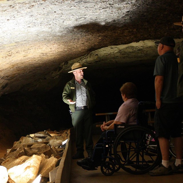 A group of visitors, one in a wheelchair, listen to a ranger.