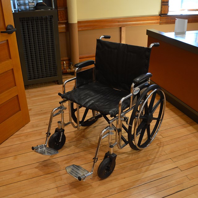 An empty wheelchair next to a desk.