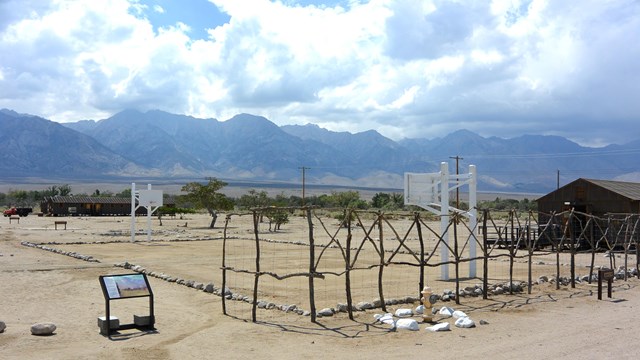 Fence in foreground, two brown buildings and a white basketball net in background