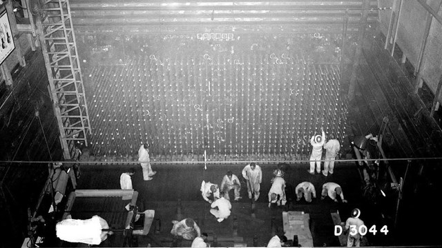 A black and white photo from overhead of a group of men working in a room.