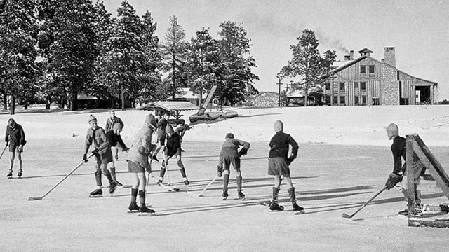 A black and white photo of a bunch of children ice skating on a frozen pond. 