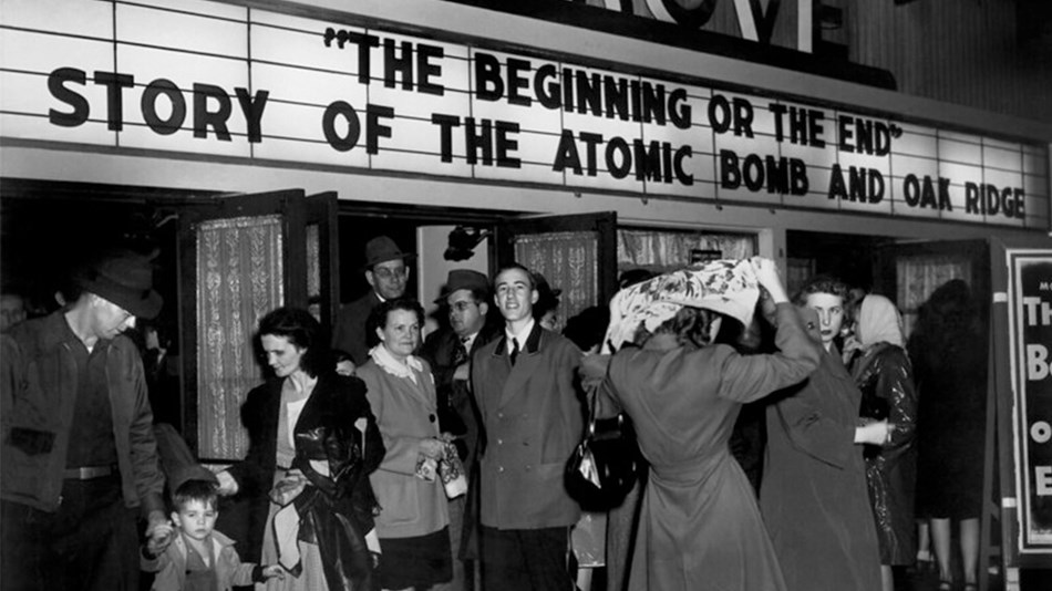 A movie theater marquee reads: “The Beginning or the End. Story of the Atomic Bomb and Oak Ridge.” 