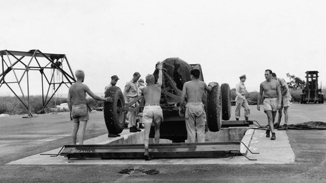 A group of men work together to lower an item into the ground.