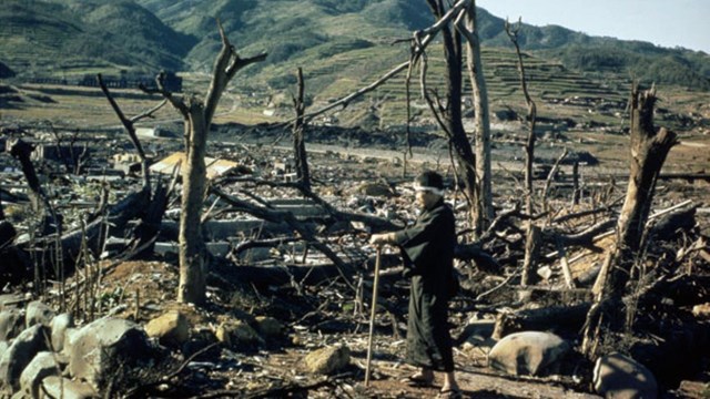 A black and white photo of ruins with a person standing in the foreground.